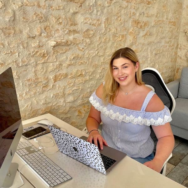 Young girl with blonde hair sat at a work desk with a computer