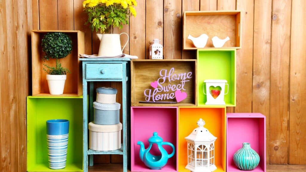 Brightly painted wooden crates styled with vases, plants, and a 'Home Sweet Home' sign create a cheerful display to elevate your home decor.
