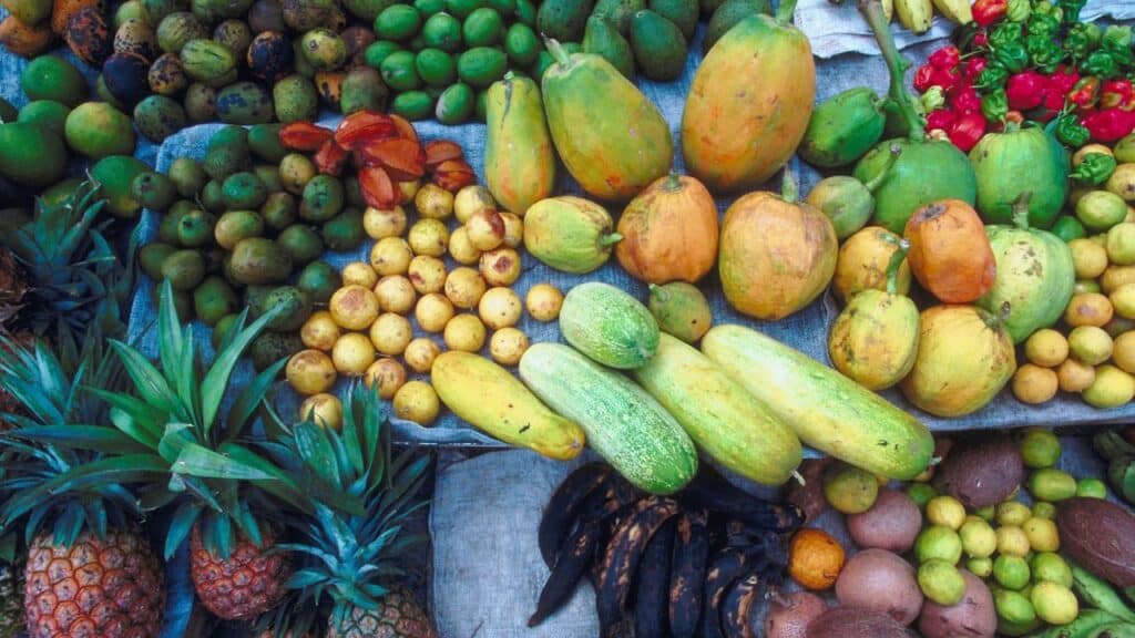 Colorful market stall filled with tropical fruits like papayas, pineapples, and mangoes, illustrating the nutritional benefits of seasonal foods in diverse diets.