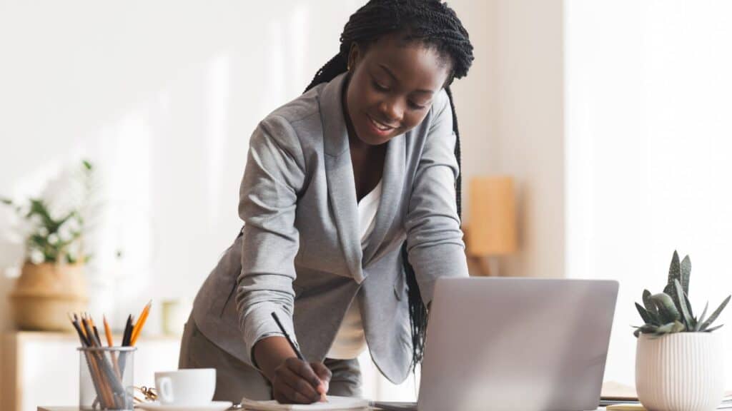 Businesswoman writing at a desk while standing, using active habits to help hit 10000 steps a day.