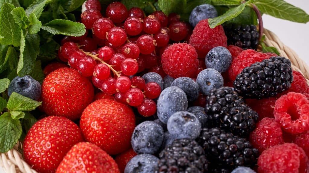 Assorted fresh berries including strawberries, blueberries, raspberries, and blackberries in a basket, highlighting the nutritional benefits of seasonal foods rich in antioxidants.