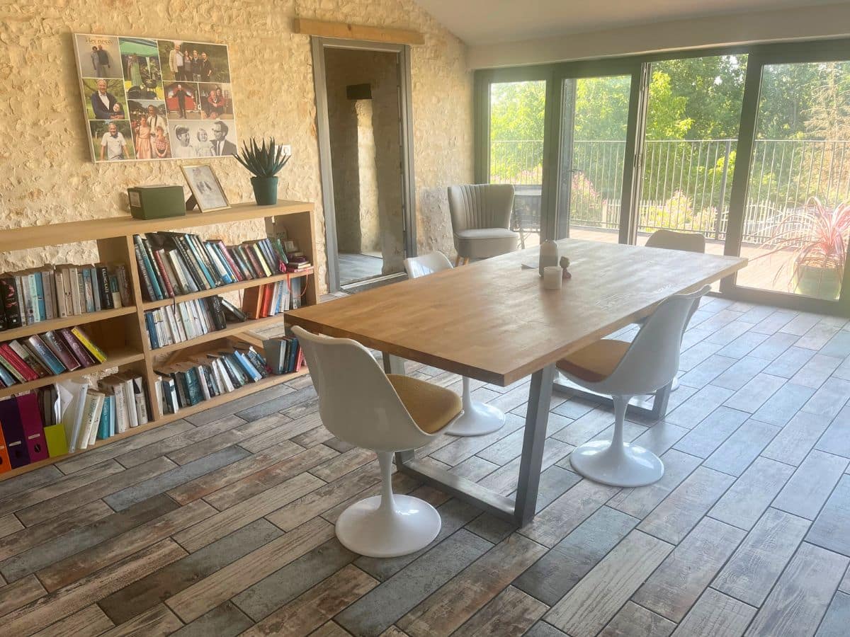 Bright dining area with a wooden table, white modern chairs, and a full wall of glass doors opening to a balcony, creating an inviting space to elevate your home decor.