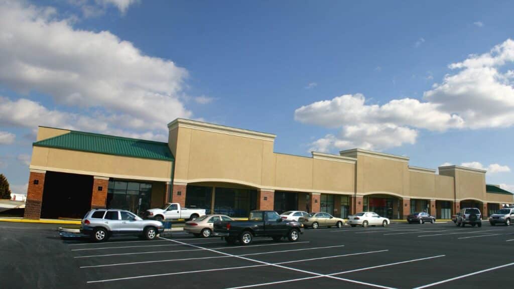 Shopping plaza with cars parked in front, where walking between stores can help hit 10000 steps a day.