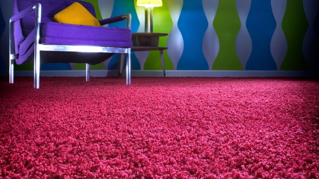 retro living room with a deep purple chair, red shag carpet, and wavy blue and green wallpaper, capturing the vibrant color and texture combinations of 70s' home design trends.
