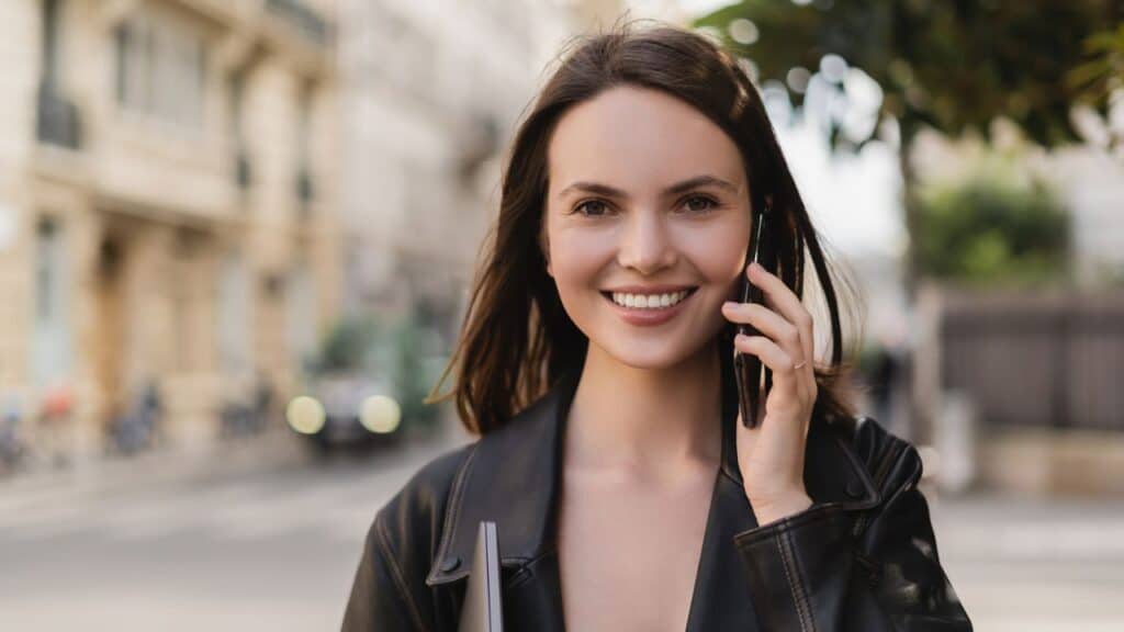 Smiling woman walking outdoors while talking on the phone, staying active to hit 10000 steps a day.
