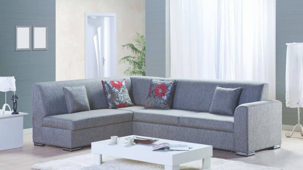 Modern gray sectional sofa with floral cushions in a bright living room, styled for balance and harmony with Feng Shui tips.