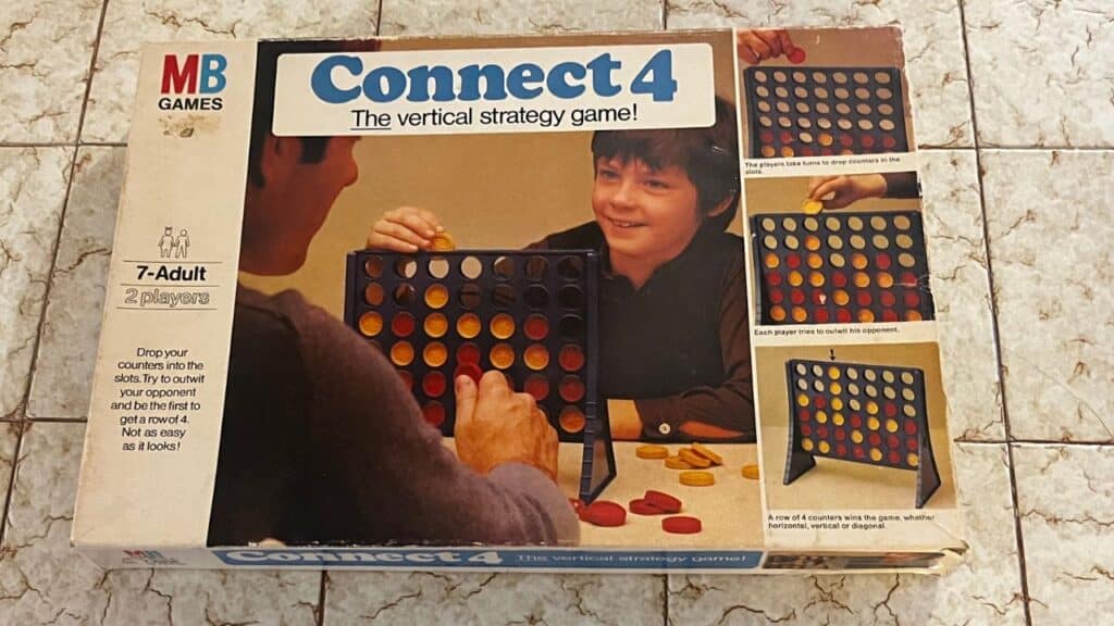 The box for Connect 4 shows two players engaged in the vertical strategy game using red and yellow discs. A staple in childhood toys from the 70s, it encouraged logic and competition.
