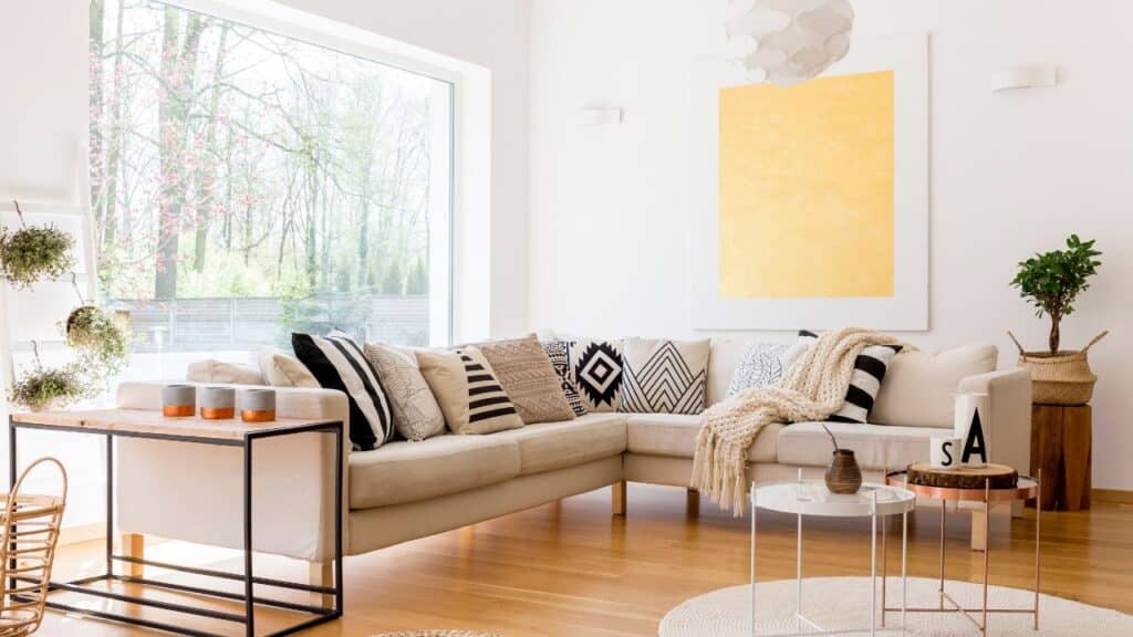 Sunlit living room with a beige sectional sofa and patterned cushions, arranged to create harmony following Feng Shui tips.