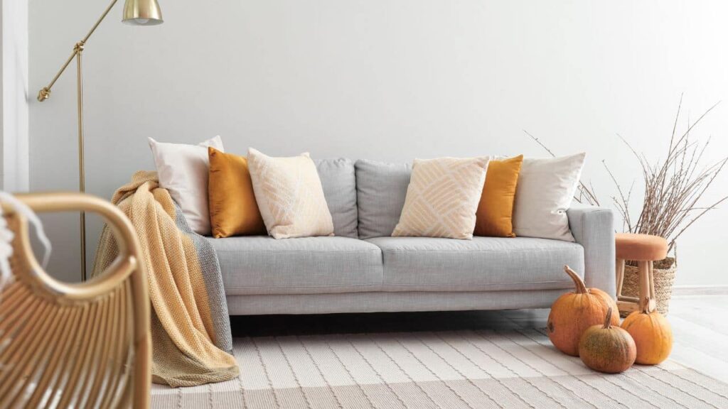 A grey couch with cushions of autumn colors.