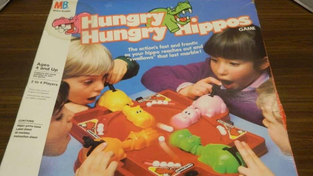 The box of Hungry Hungry Hippos features excited children playing with colorful plastic hippos gobbling marbles on a red base. It’s one of the most iconic childhood toys from the 70s for fast-paced fun.
