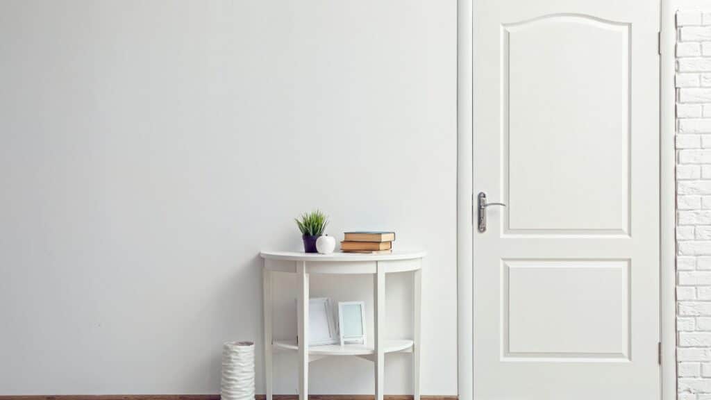 Minimalist entryway with a white console table, books, and a plant, styled for good energy flow using Feng Shui tips.