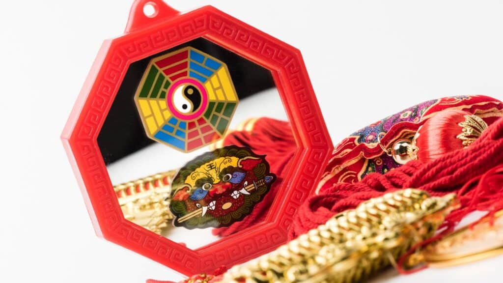 Red Feng Shui Bagua mirror with a yin-yang symbol and protective design, used for attracting harmony and good fortune.