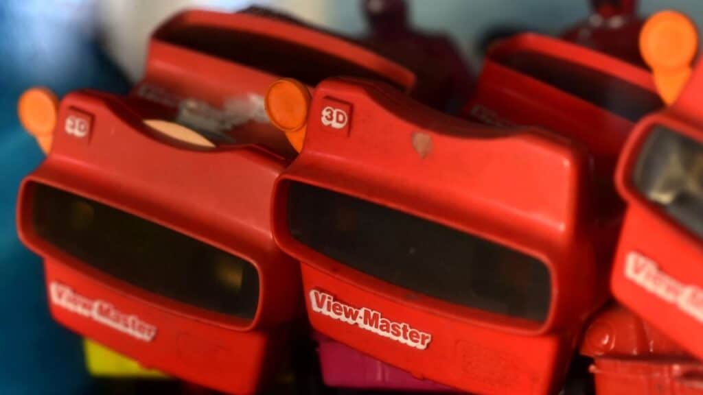 A close-up of red View-Master 3D viewers with orange levers stacked together, highlighting their nostalgic design. This classic stereoscopic toy was a visual adventure staple in childhood toys from the 70s.