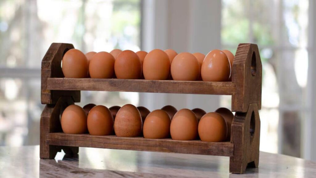 A rustic wooden egg rack holding brown eggs on a kitchen counter, featuring a simple but practical kitchen tool for egg storage.