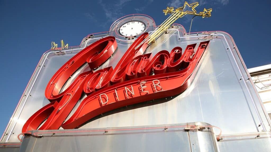 Close-up of the Galaxy Diner sign in bright red neon against a blue sky with a vintage-style clock and shooting star detail. A flashy and photogenic diner along Route 66.