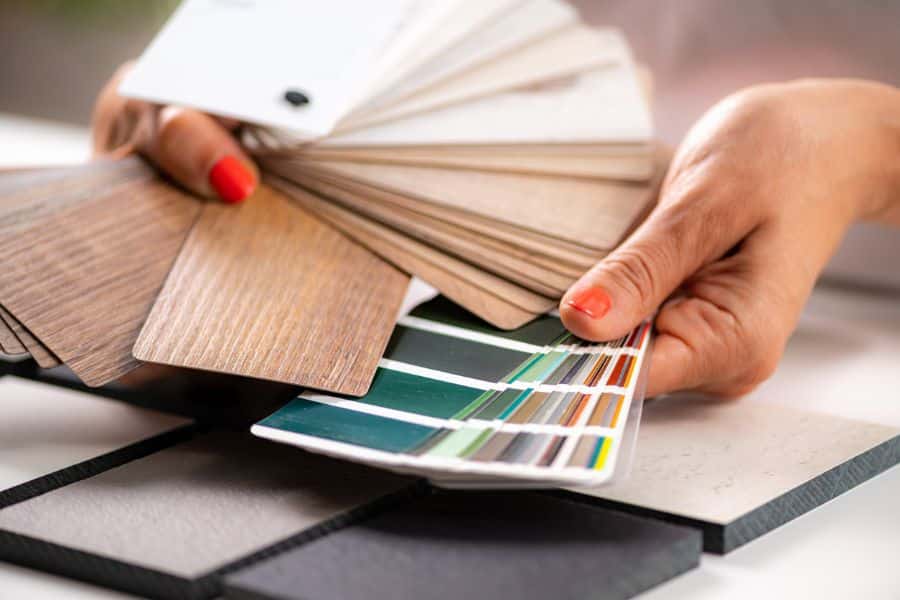 Close-up of hands flipping through samples of wood textures and paint swatches, ideal for highlighting consulting or interior design as part-time retiree-friendly jobs.