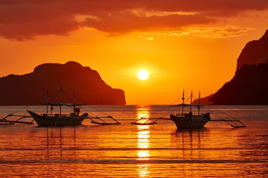 Traditional outrigger boats floating on calm orange-hued water during a vibrant sunset, with limestone cliffs in the distance.
Lisbon cityscape, Portugal: Colorful buildings with red-tiled roofs in L