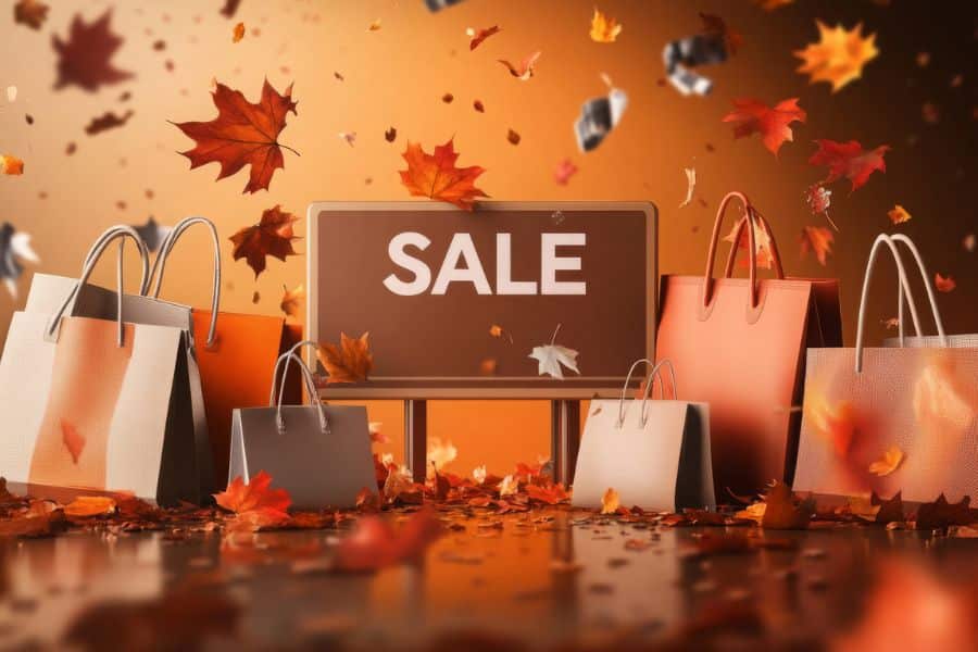 Autumn-themed sale display with shopping bags and falling leaves surrounding a large “SALE” sign, showing how seasonal discounts can be a smart way to save money.