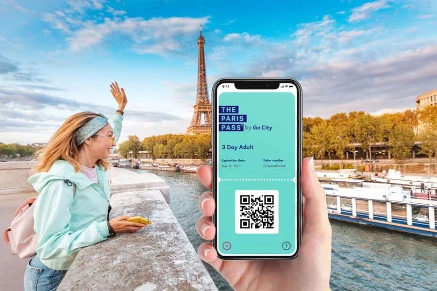 A woman waves near the Eiffel Tower while someone holds a smartphone showing a digital Paris Pass, showcasing sightseeing travel hacks with city passes.