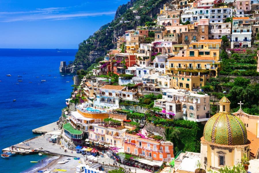 Colorful cliffside homes cascade down the hillside in Positano, overlooking the deep blue Mediterranean Sea. This stunning coastal village perfectly represents the charm of Beautiful Italian Regions.