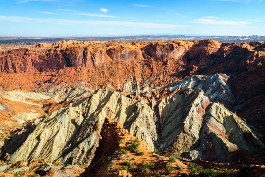 Colorful, jagged cliffs of Capitol Reef National Park in Utah with striking contrasts of red and white rock layers. Its remote location and limited amenities contribute to its placement among national parks to avoid for those seeking convenience.