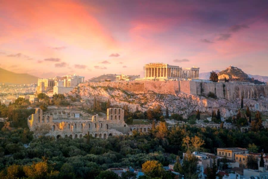 A dramatic sunset over the Acropolis in Athens, Greece, highlighting the ancient Parthenon on a rocky hilltop. Greece is repeatedly listed as one of the countries that welcome Americans, especially history lovers.