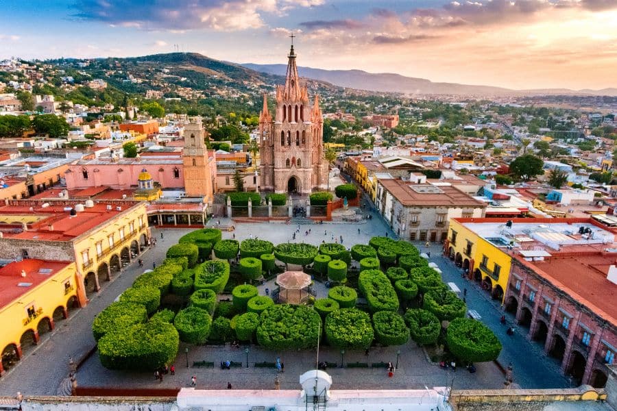 Aerial view of the vibrant historic center of San Miguel de Allende, Mexico, with the Parroquia de San Miguel Arcángel rising above a manicured town square. Mexico continues to be one of the most popular countries that welcome Americans for both travel and retirement.