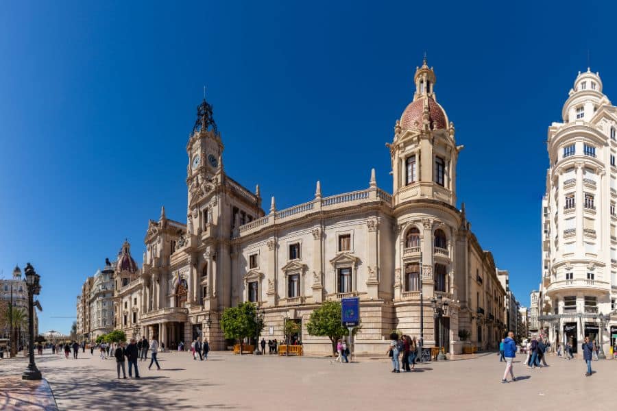 A bustling plaza in front of the historic city hall in Valencia, Spain, framed by ornate architecture and a bright blue sky. Spain is one of the top European countries that welcome Americans, offering a rich culture and warm climate.