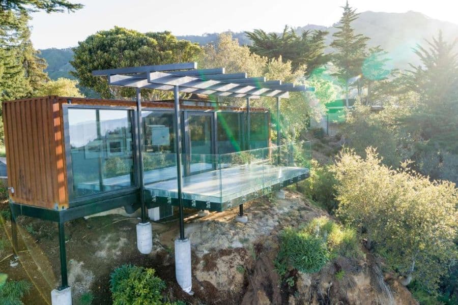A modern glass-walled suite on stilts overlooks a forested mountainside, showcasing eco-luxury design at one of the unique All-Inclusive Resorts in the US.