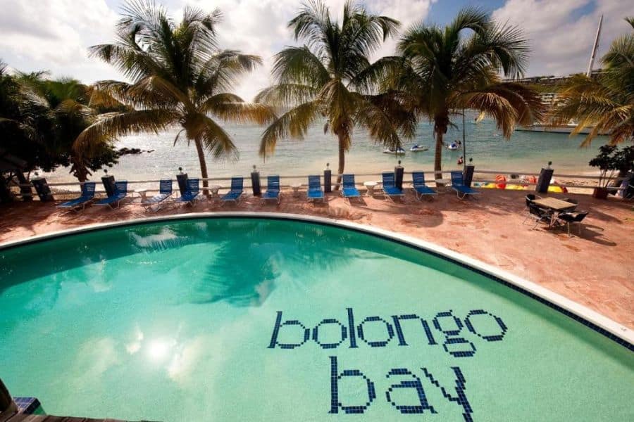 A beachfront pool with “Bolongo Bay” tiled on the floor is surrounded by palm trees and lounge chairs, highlighting a tropical escape among All-Inclusive Resorts in the US.