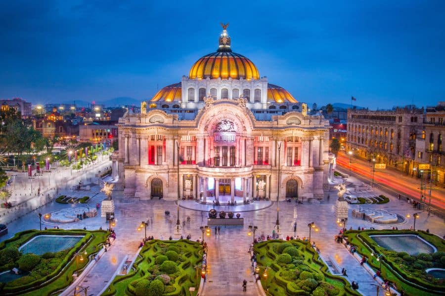 The illuminated Palacio de Bellas Artes in Mexico City at dusk, representing the cultural experiences you can enjoy when you Live on a Cruise Ship and travel internationally.