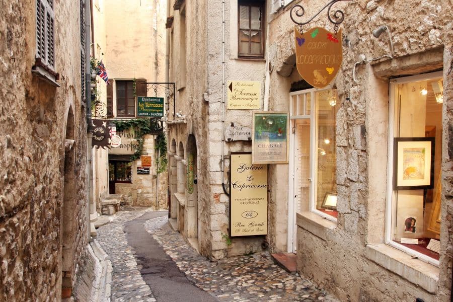 A winding cobblestone alley in Saint-Paul-de-Vence, France, lined with rustic shops and art galleries, highlights the artistic soul of Medieval Places to Visit in Europe.