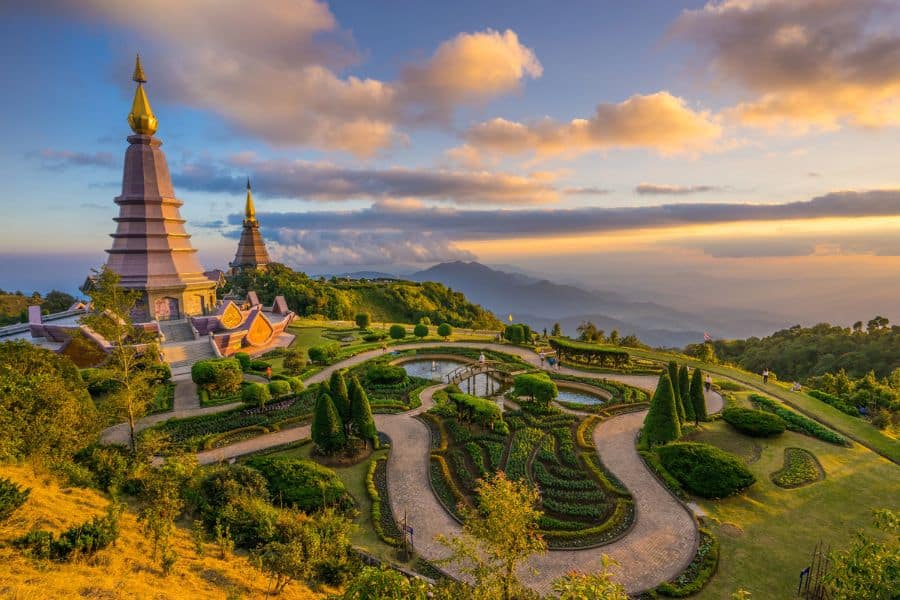 Twin pagodas and manicured gardens at sunset in the mountains of Thailand, a peaceful scene you might visit on a long-term journey to Live on a Cruise Ship.