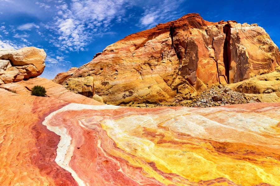 Vivid swirls of red, orange, and yellow sandstone under a deep blue sky in a remote desert canyon, a geological wonder among America’s Best-Kept Hiking Secrets.