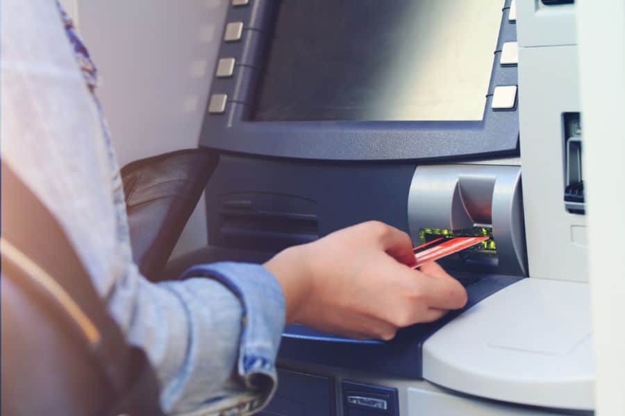 A close-up of a person withdrawing money from an ATM using a bank card—often a necessary step when US credit cards don’t work in this European city and cash is still king.