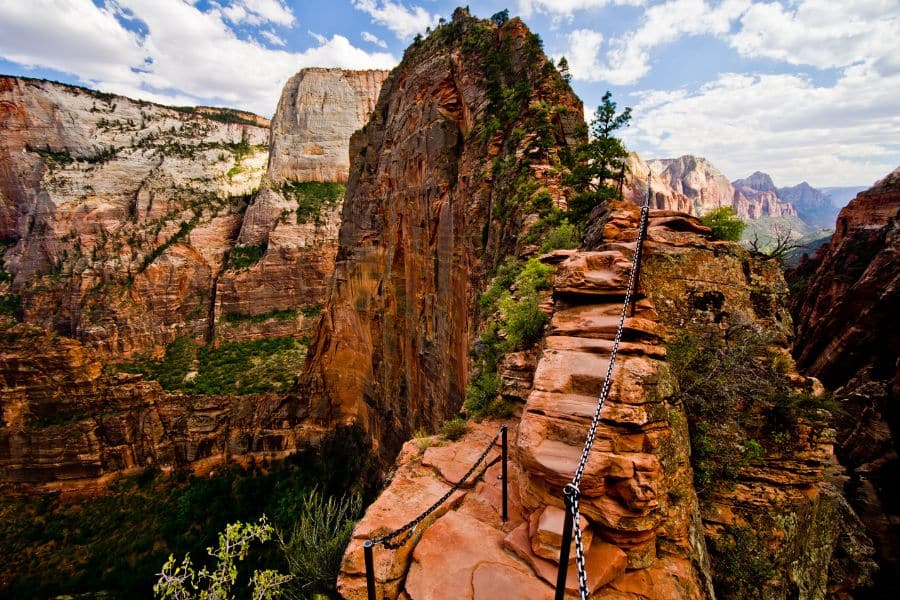 A narrow trail clings to a cliff edge with chains for support along Angel’s Landing in Zion National Park, Utah. This adrenaline-pumping route is among the most thrilling hiking trails in the US.