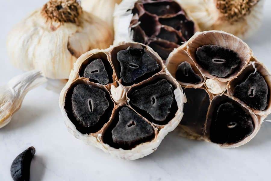 A close-up of black garlic cloves, sliced open to reveal their soft, dark interiors. Black garlic is rich in antioxidants and appears on the list of 7 Foods That Actively Fight Wrinkles.
