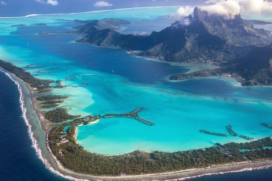 Aerial view of Bora Bora’s turquoise lagoon with overwater bungalows and a volcanic peak rising in the background. This tropical paradise is one of the ultimate Bucket List Destinations to Visit.