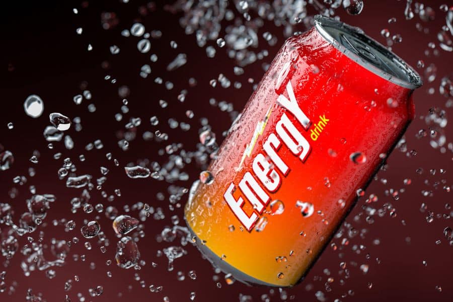 Close-up of a red and yellow energy drink can surrounded by water droplets, highlighting energy drinks as one of the 9 common foods to avoid.