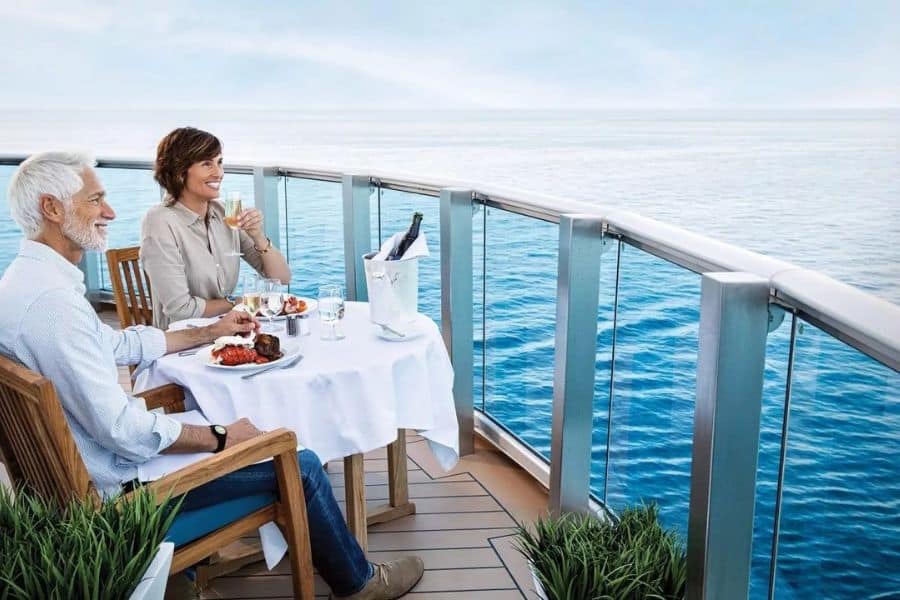 Smiling couple dining on a private cruise balcony, suggesting missing out on premium experiences is one of the Mistakes To Avoid On Your Next Cruise.
