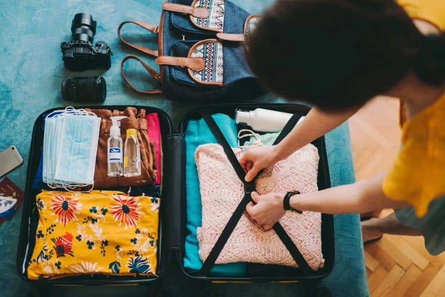 Top view of a suitcase being packed with organized clothing, toiletries, and accessories, emphasizing poor packing as one of the Mistakes To Avoid On Your Next Cruise.
