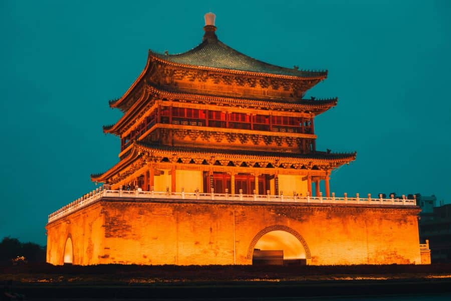 The illuminated Bell Tower in Xi’an, China, glows against a deep teal evening sky. Cultural landmarks like this make Xi’an one of the essential Bucket List Destinations to Visit.
