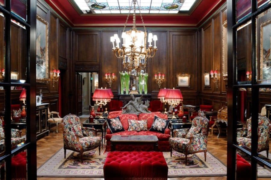 Lavish lounge with floral furniture, red velvet accents, and a grand chandelier — a richly decorated space that reflects the grandeur of European Hotels Where Famous Writers Lived.