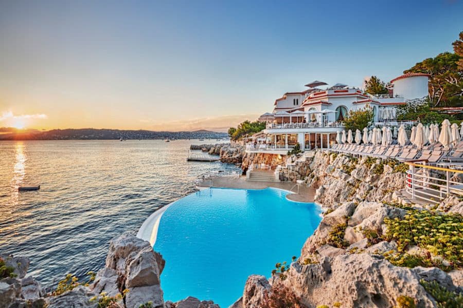 A luxurious seaside hotel with an infinity pool carved into the rocks on the French Riviera — an inspiring setting among European Hotels Where Famous Writers Lived.