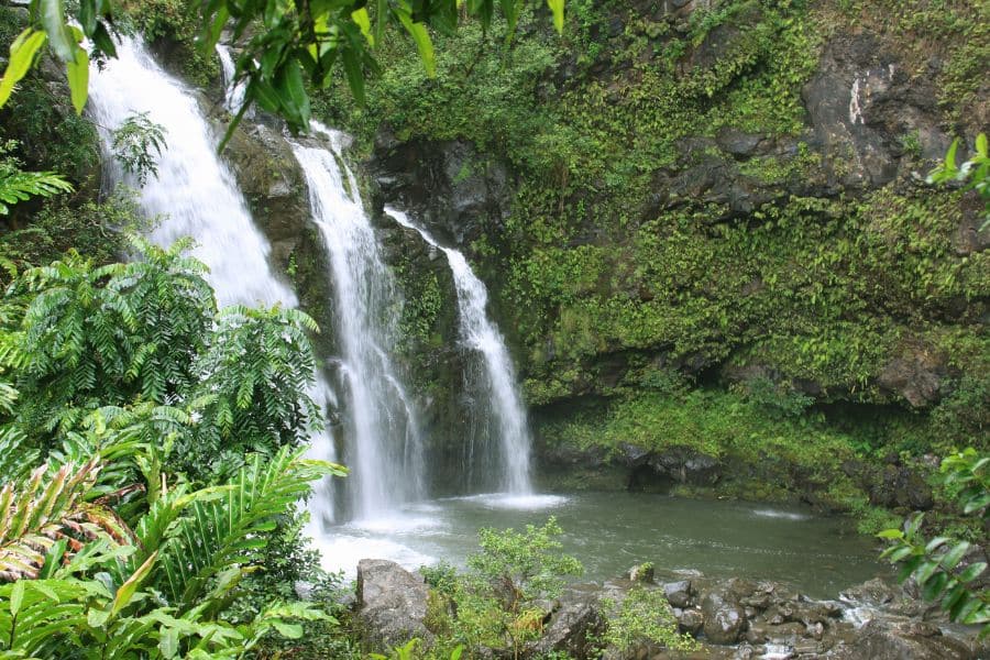 Twin waterfalls cascade into a serene jungle pool surrounded by dense greenery along the Road to Hana in Maui. Hidden gems like this make Hawaii a dream Bucket List Destination to Visit.