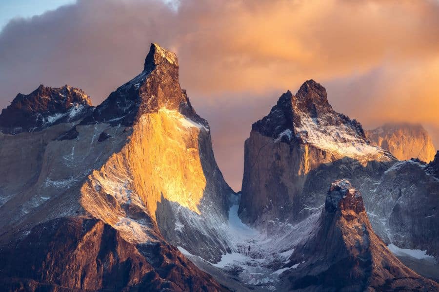 Dramatic sunrise illuminates the jagged peaks of Torres del Paine in Patagonia, Chile. Towering granite spires like these make the national park a favorite among Bucket List Destinations to Visit.