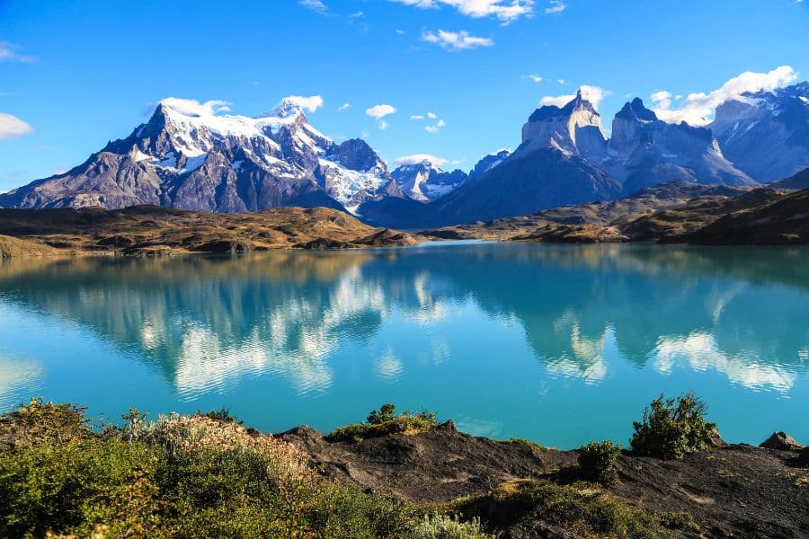 Turquoise lake reflects snow-capped mountains and rugged peaks in Torres del Paine National Park, Chile. This untouched wilderness is a standout among Bucket List Destinations to Visit.