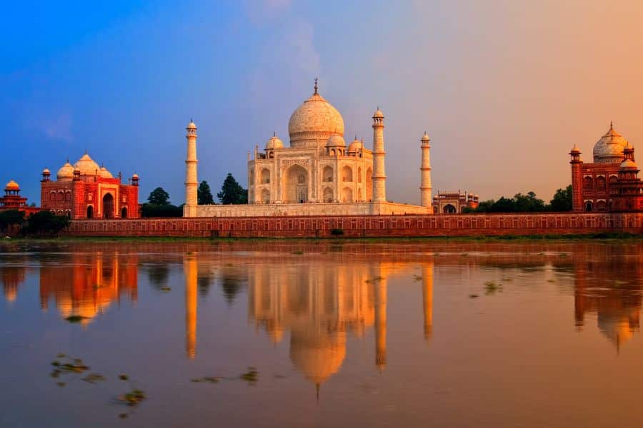 The iconic white marble Taj Mahal glows in the soft light of sunset, reflected in the Yamuna River. A symbol of love and architectural wonder, it's a crown jewel among Bucket List Destinations to Visit.