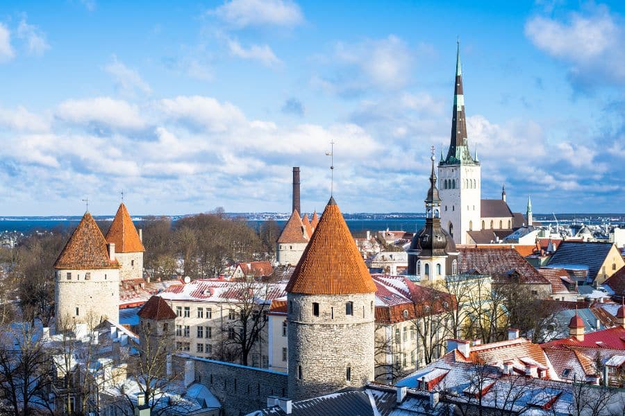 Aerial winter view of Tallinn, Estonia, with red-roofed towers and the spire of St. Olaf’s Church – a snow-covered wonder among Medieval Towns in Europe.