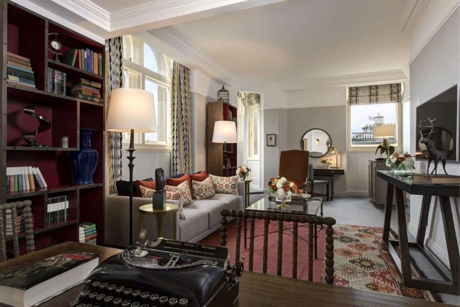 Stylish hotel suite with a homey touch, filled with books, antique decor, and a view from the window — blending comfort and inspiration in European Hotels Where Famous Writers Lived.